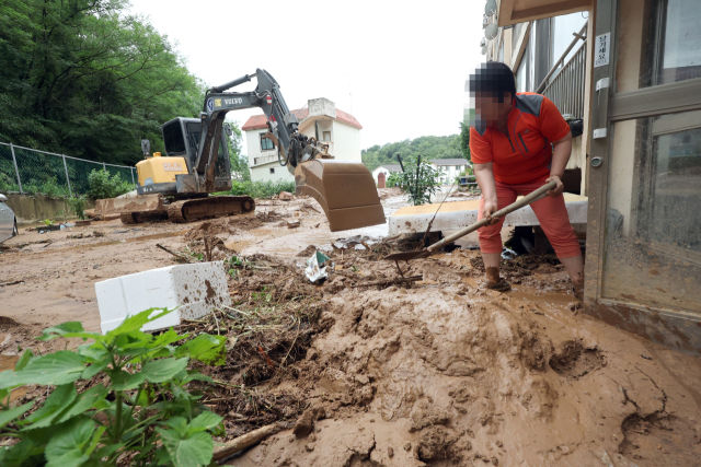 한 주민이 10일 폭우로 산사태가 나면서 전북 군산시 성산면의 한 아파트로 내려온 토사를 걷어내고 있다. 연합뉴스