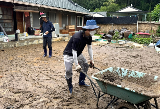 12일 오전 충북 영동군 심천면의 한 수해 주택에서 자원봉사자들이 마당에 쌓인 진흙을 퍼내고 있다. 연합뉴스