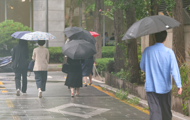 16일 오후 서울 종로구 광화문 광장에서 시민들이 우산을 쓰고 이동하고 있다. 연합뉴스