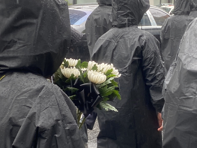 18일 서이초 순직 교사 1주기 추모 걷기 행사에 참석한 한 교사가 한 손 가득 국화 다발을 들고 행진하고 있다. 이승령 기자