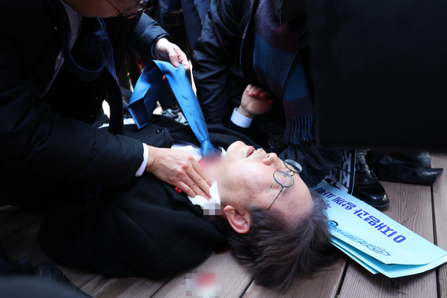 이재명 더불어민주당 전 대표가 지난 1월 2일 부산 가덕도 신공항 부지를 둘러본 후 기자들과 문답을 진행하던 중 왼쪽 목 부위에 습격을 당해 피를 흘린 채 쓰러져 있다. 연합뉴스