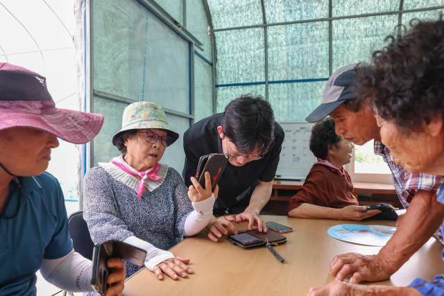 총리실 직원(가운데)이 경남 창녕군에서 어르신들이 받은 ‘자녀 경보’ 메시지를 살펴보고 있다. 한덕수 국무총리 페이스북 캡쳐.