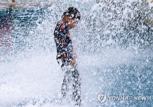 전국 대부분 지역에 폭염특보가 발효된 25일 광주 북구 시민의숲 물놀이장에서 아이가 떨어지는 물줄기를 맞고 있다. 광주=연합뉴스