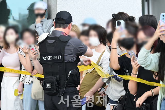 팬이 라인을 찢자 공항 경찰이 이를 잡고 서 있다.