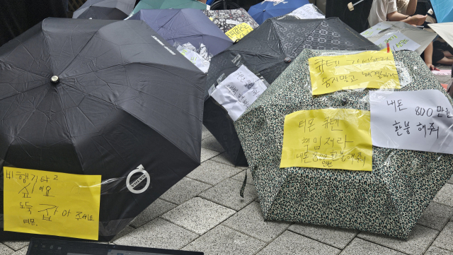 티몬·위메프 환불 지연 피해자가 28일 서울 강남구 큐텐 본사 건물 앞에서 우산을 들고 나와 항의 퍼포먼스를 선보이고 있다. 채민석 기자