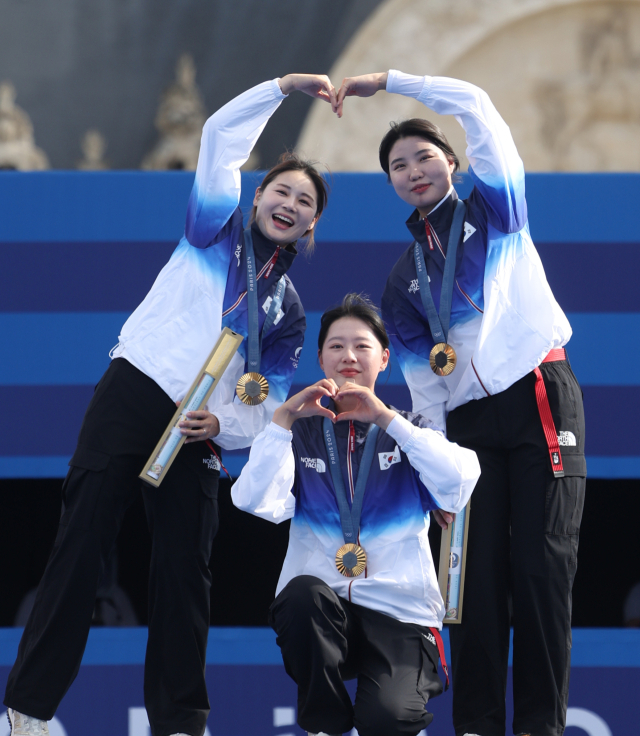 올림픽 10연패를 달성한 한국 여자 양궁대표팀의 남수현(오른쪽부터), 임시현, 전훈영이 28일(현지시간) 프랑스 파리 레쟁발리드 양궁 경기장에서 열린 2024 파리올림픽 양궁 여자단체 시상식에서 금메달을 목에 걸고 하트를 만들며 기념 촬영을 하고 있다. 연합뉴스