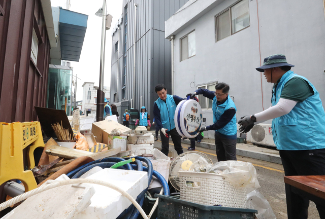 지난달 19일 충남 당진시 당진전통시장에서 현대제철 당진제철소 관계자들이 빗물에 젖은 집기류를 옮기고 있다. 연합뉴스