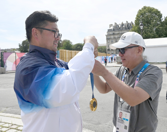 김우진(왼쪽)이 4일(현지시간) 프랑스 파리 앵발리드에서 열린 2024파리올림픽 양궁 남자 개인 결승에서 굼매달을 차지한 후 정의선 대한양궁협회 회장에게 금메달을 걸어주고 있다. 파리=성형주 기자