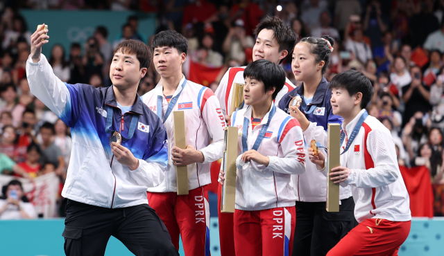 지난달 30일(현지시간) 프랑스 파리 사우스 파리 아레나4에서 열린 2024 파리올림픽 탁구 혼합복식 시상식에서 동메달을 차지한 한국 임종훈, 신유빈과 은메달을 차지한 북한 리정식, 김금용 등이 시상대에서 삼성 Z플립 6로 함께 기념촬영을 하고 있다. 연합뉴스