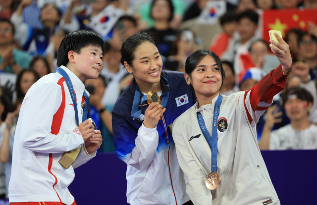 대한민국 배드민턴 대표팀 안세영 선수가 5일 오후(한국시간) 프랑스 파리 라 샤펠 아레나에서 열린 2024 파리올림픽 배드민턴 여자 단식 시상식에서 은메달을 획득한 중국 허빙자오와 동메달을 획득한 인도네시아 그리고리아 툰중과 갤럭시 Z플립6를 활용해 기념촬영을 하고 있다. 뉴스1