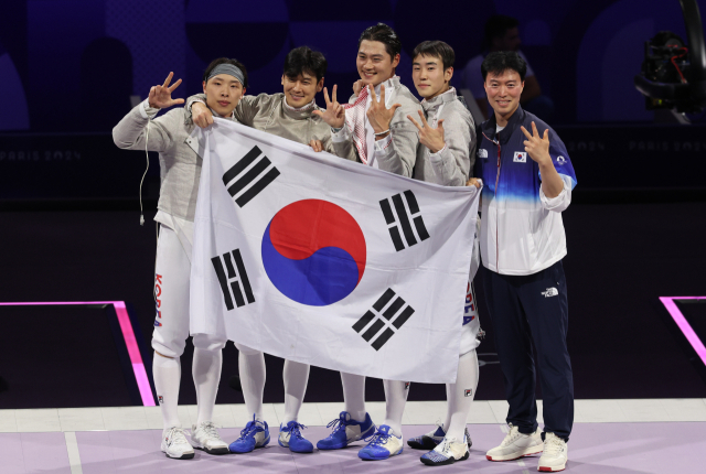 남자 사브르 대표팀이 31일(현지시간) 프랑스 파리 그랑 팔레에서 열린 2024 파리올림픽 펜싱 사브르 남자 단체 헝가리와 결승에서 승리해 올림픽 3연패를 달성한 뒤 태극기를 들고 자축하고 있다. 연합뉴스