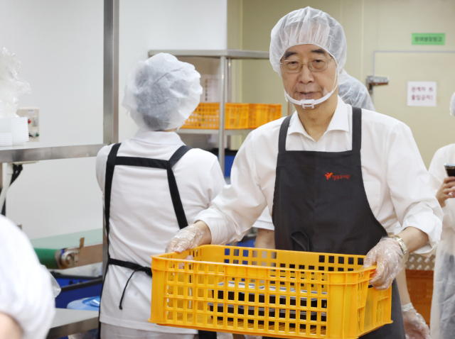 한덕수 국무총리가 8일 서울 성북구에서 관계자의 안내에 따라 방학 중 결식 우려 아동들을 위한 도시락을 포장한 후 이동하고 있다. 연합뉴스