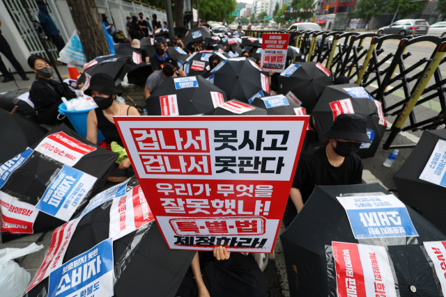 티몬·위메프(티메프) 피해 판매자와 소비자들이 이달 18일 오후 서울 종로구 금융위원회 앞에서 열린 ‘검은 우산 집회’에 참가해 우산을 펴고 자리에 앉아 있다. 연합뉴스.