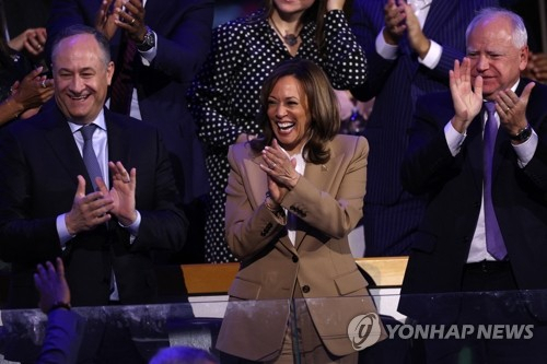 미국 민주당 대통령 후보인 카멀라 해리스 부통령(가운데)과 그의 남편 더글러스 엠호프(왼쪽), 러닝메이트(부통령 후보) 팀 월즈 미네소타 주지사가 19일(현지시간) 일리노이주 시카고 유나이티드 센터에서 열린 민주당 전당대회 첫날 조 바이든 대통령의 연설에 기립박수를 치고 있다. 로이터=연합뉴스