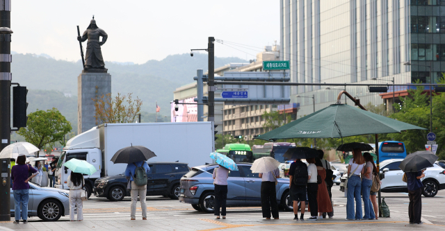 서울 지역에 퇴근길 소나기가 내린 19일 서울 세종로사거리 시민들이 우산을 쓴 채 횡단보도 신호를 기다리고 있다. 연합뉴스