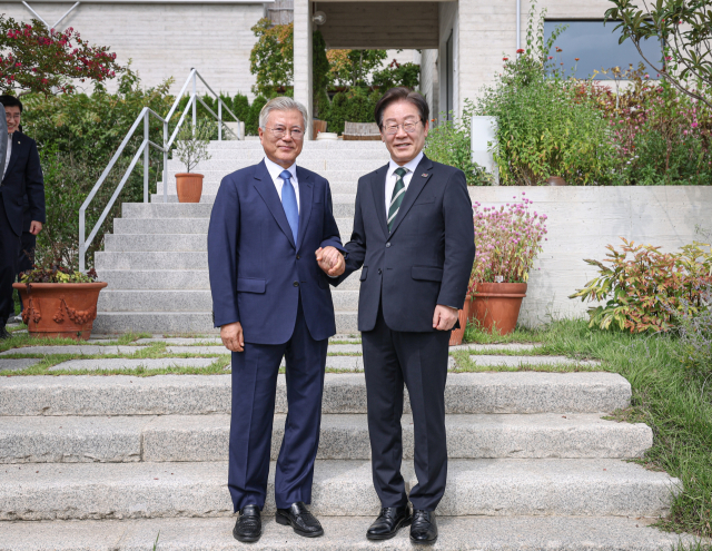 문재인 전 대통령이 8일 경남 양산 평산마을 사저를 예방한 이재명(오른쪽) 더불어민주당 대표와 손을 잡고 기념촬영 하고 있다. 사진 제공=더불어민주당