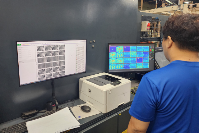 넥센타이어 관계자가 공장에 적용된 인공지능(AI) 제품 검사 자동화 플랫폼을 통해 미세한 결함이 있는지를 확인하고 있다. 사진제공=넥센타이어