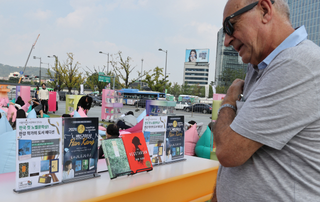 11일 서울 광화문광장 책마당 행사장에서 외국인이 노벨문학상을 수상한 한강의 소설책을 보고 있다. 연합뉴스