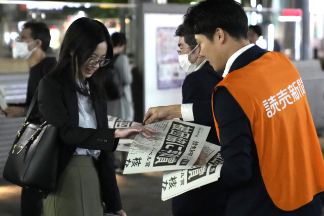 요미우리신문 직원이 11일 도쿄에서 니혼히단쿄가 노벨평화상을 수상한 소식을 실은 호외를 나눠주고 있다. AP연합뉴스