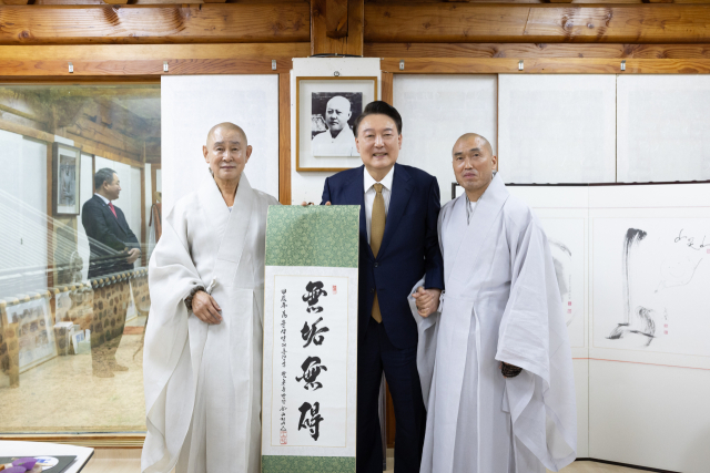 윤석열 대통령이 22일 부산 금정구 범어사를 찾아 차담 뒤 주지 정오스님(오른쪽)이 쓴 무구무애(無垢無碍) 족자를 선물 받은 뒤 기념촬영을 하고 있다. 왼쪽부터 방장 정여스님, 윤 대통령, 주지 정오스님. 부산=연합뉴스