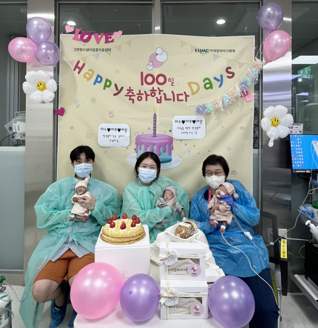 세 쌍둥이의 가족들이 이대서울병원 신생아집중치료실에서 100일 축하 기념 촬영을 하고 있다. 사진 제공=이대엄마아기병원