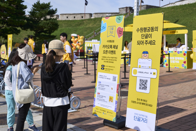 수원화성 장안문을 찾은 시민들이 ‘수원 행궁동 카카오톡 채널 오픈 이벤트’ 홍보물을 살펴보고 있다. 사진 제공=카카오