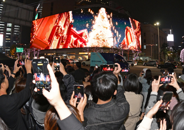 1일 개최된 2024 명동스퀘어 점등식을 관람하기 위해 몰려든 시민들이 신세계백화점 본점 본관 전광판에 비춰진 영상을 휴대폰으로 촬영하고 있다. 성형주 기자