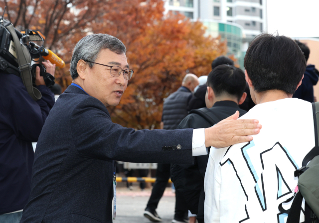 정근식 서울시교육감이 14일 서울 서초구 반포고등학교 앞에서 수능을 치르는 수험생의 어깨를 두드리며 응원하고 있다. 연합뉴스