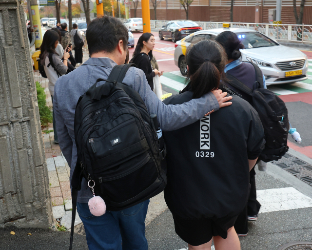 대학수학능력시험이 진행된 14일 오후 부산 해운대구 센텀여자고등학교에서 한 학부모가 고생한 딸에게 꽃다발을 전달하고 가방을 들어주고 있다. 연합뉴스