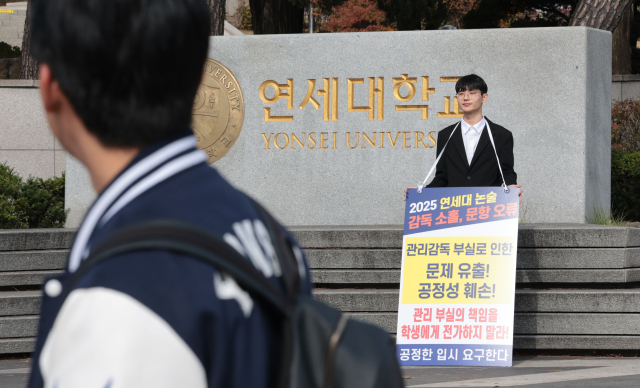 이달 4일 서울 서대문구 연세대학교 정문 앞에서 연세대 재시험 집단소송의 후원자 중 한 명인 정모씨가 논술문제 유출 등을 규탄하며 1인 시위를 하고 있다. 연합뉴스