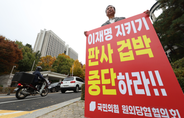 이재명 더불어민주당 대표의 공직선거법상 허위사실 공표 혐의에 대한 1심 판결을 하루 앞둔 14일 서울 서초구 서울중앙지법 앞에서 한 국민의힘 원외 당협위원장이 야당의 검사탄핵 추진 규탄 릴레이 피켓팅을 하고 있다. 연합뉴스