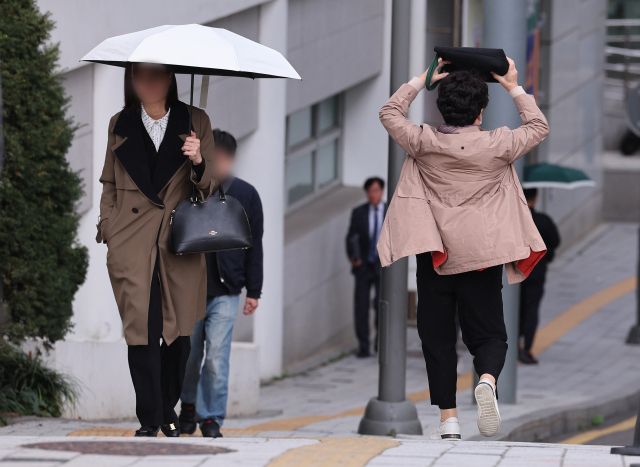 흐린 날씨를 보인 6일 오전 서울 시내 한 대학병원에서 비가 내리자 한 시민이 가방으로 머리를 가리고 뛰고 있다. 연합뉴스