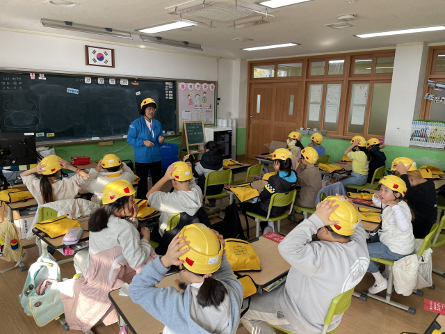 이달 21일 울진 죽변초등학교에서 열린 ‘재난안전 경안전모 전달식 및 재난안전교육’ 행사에서 학생들이 모의 훈련을 하고 있다. 사진 제공=현대건설