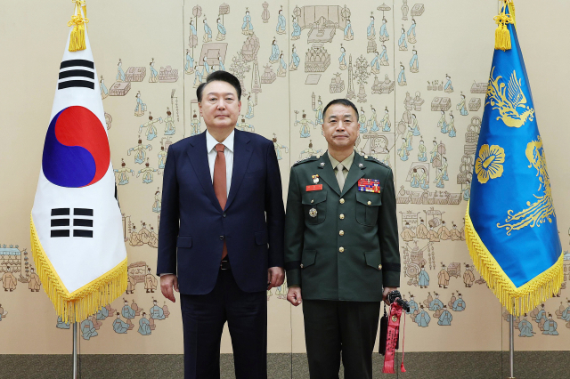 윤석열 대통령이 27일 서울 용산 대통령실 청사에서 열린 중장 진급·보직 신고 및 삼정검 수치 수여식에서 주일석 해병대사령관의 삼정검에 수치를 달아준 뒤 기념촬영을 하고 있다. 연합뉴스