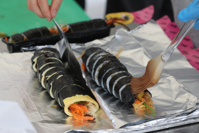 한 김밥집 직원이 김밥에 참기름을 바르고 있다. 연합뉴스