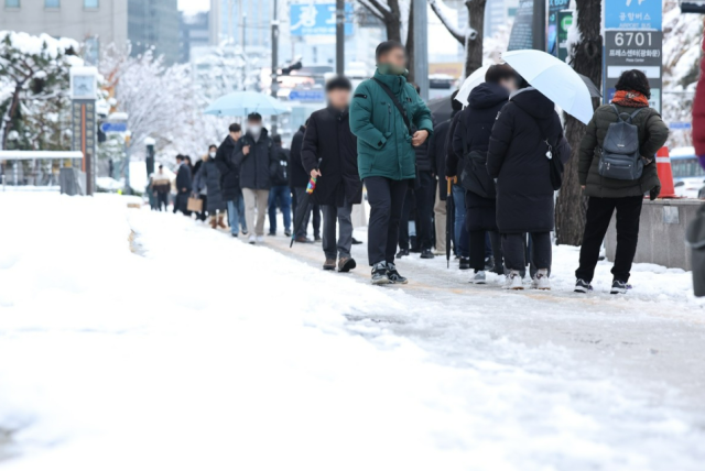 이틀 연속 폭설이 내린 28일 오전 서울 중구 세종대로 일대에서 시민들이 출근하고 있다. 연합뉴스