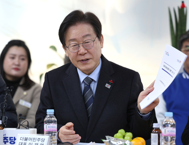 이재명 더불어민주당 대표가 1일 오후 경북 포항시 북구 죽도동 포항시전통시장상인연합회 사무실에서 열린 포항 전통시장 상인회 간담회에서 지역사랑상품권 발행 지원 건의안을 들어 보이고 있다. 연합뉴스