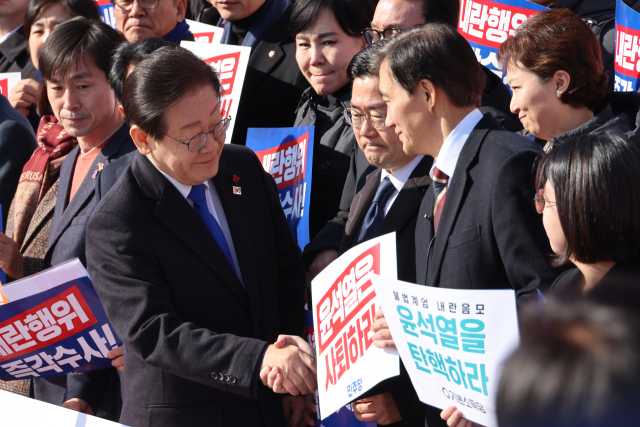 이재명 더불어민주당 대표와 조국 조국혁신당 대표가 4일 국회 본청 앞 계단에서 열린 '윤석열 대통령 사퇴촉구 탄핵추진 비상시국대회'에서 만나 악수하고 있다. 연합뉴스