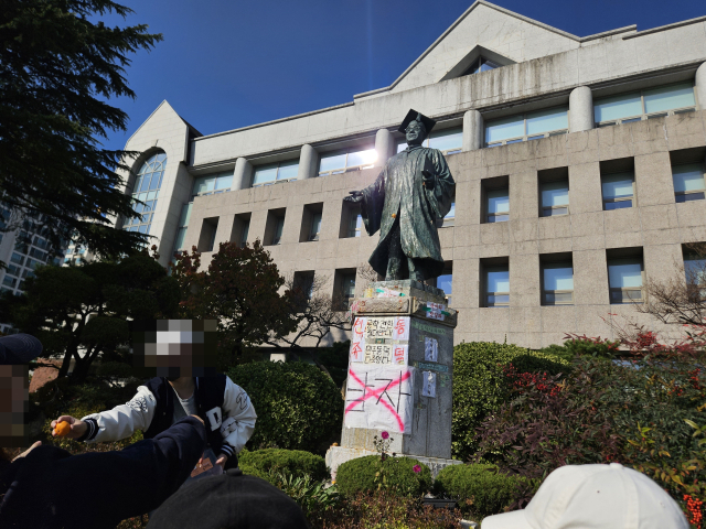 지난달 12일 서울 성북구 동덕여대 캠퍼스에 설치된 동덕학원 창립자 조동식 선생의 동상에 학생들이 항의의 의미로 귤을 던지고 있다. 박민주 기자