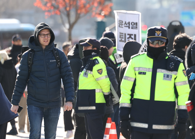 윤석열 대통령이 긴급 대국민 담화를 통해 비상계엄 해제를 선언한 4일 오전 서울 종로구 광화문광장에서 한 외국인 관광객이 계엄 규탄 집회를 지켜보고 있다. 연합뉴스