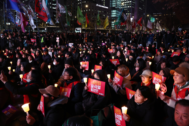 4일 오후 서울 동화면세점 앞에서 전국민주노동조합총연맹 주최로 열린 ‘내란죄 윤석열 퇴진! 시민촛불’에서 참가자들이 촛불을 들고 있다. 연합뉴스