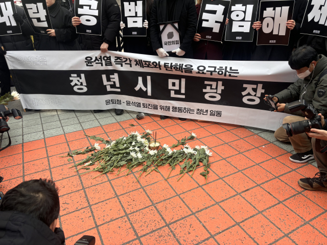 청년 단체 '윤석열 퇴진을 위해 행동하는 청년들(윤퇴청)'이 탄핵소추안 표결에 참여하지 않은 105명의 여당 의원을 뜻하는 105송이의 국화를 헌화하고 있다. 장형임 기자
