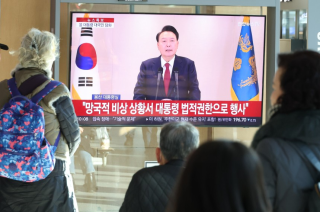 12일 오전 서울역에서 시민들이 윤석열 대통령 담화 생중계 영상을 TV로 보고 있다. 연합뉴스