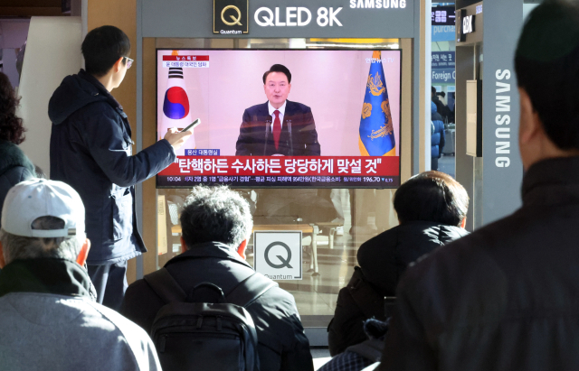 12일 오전 서울역에서 시민들이 윤석열 대통령 담화를 TV로 보고 있다. 연합뉴스