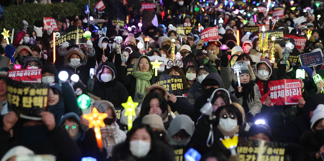 윤석열 대통령에 대한 국회의 2차 탄핵소추안 표결을 하루 앞둔 13일 오후 서울 영등포구 여의도 국회 앞에서 열린 '윤석열 즉각 탄핵 구속 촉구 촛불문화제'에서 참가자들이 응원봉과 손피켓을 들어 보이고 있다. 뉴스1