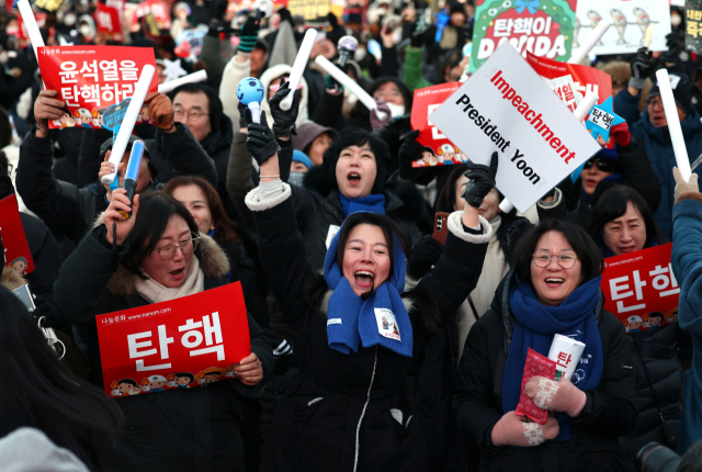 윤석열 대통령 탄핵소추안이 가결된 14일 서울 여의도 국회 앞에서 열린 집회에 참석한 시민들이 환호하고 있다. 연합뉴스