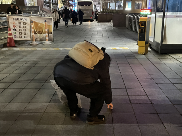 13일 밤 종량제 봉투를 들고 나온 시민이 여의도 국회 일대 집회 현장에서 쓰레기를 줍고 있다. 김수호 기자