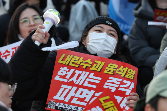 지난 15일 오후 서울 종로구 광화문광장 인근에서 시민단체 촛불행동 주최로 열린 '내란수괴 윤석열 헌재는 즉각 파면하라' 집회에서 참가자들이 윤석열 대통령의 체포 및 파면을 촉구 손팻말과 응원봉을 들고 있다. 연합뉴스