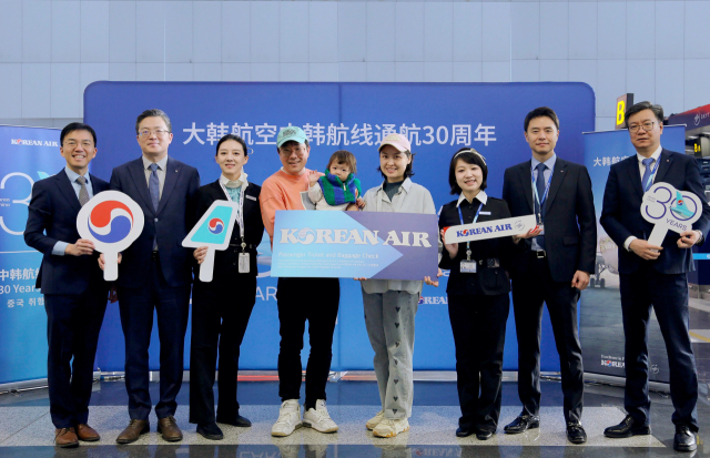 지난 22일(현지시간) 베이징 서우두 국제공항에서 열린 중국 노선 취항 30주년 기념행사에서 KE2202편 30번째 탑승수속 승객인 리우 지아시씨(오른쪽 네 번째)가 한국행 왕복 비즈니스 항공권 1매를 전달받고 대한항공 관계자들과 기념 촬영하고 있다. 사진제공=대한항공