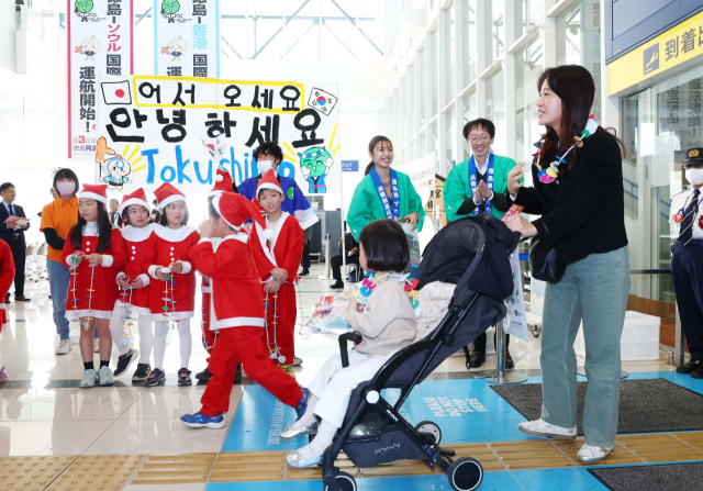 26일 일본 도쿠시마공항에서 열린 '이스타항공 도쿠시마 첫 취항' 기념 행사에서 한국 탑승객들이 도쿠시마 유치원생들로부터 목걸이를 선물받고 있다. 도쿠시마=권욱 기자 2024.12.26